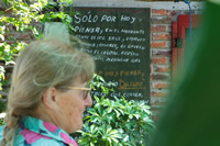 Ana, una mujer de pelo canoso y trenza aparece de perfil, delante de un cartel con un mensaje que no llega a leerse completo.