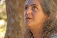Primer plano de perfil de Ana Lucía, una mujer de pelo largo canoso y ojos marrones, mirando haca arriba.