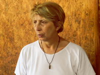 Primer plano de Blanca, de pelo rubio y una blusa color blanco, recostada contra una pared de madera compensada.