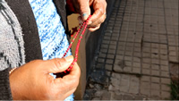 Primer plano de las manos de Isabel sosteniendo un Rosario de color rojo.