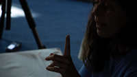 Primer plano de perfil de Mariana, hablando con el dedo índice apuntando hacia arriba.