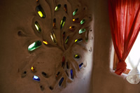 Pared interior de la casa de barro, con pequeños vidrios de colores incrustados.