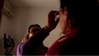 Vilma le toca la frente a Emilia que tiene los ojos cerrados.