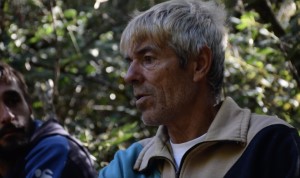 Pimienta es un hombre delgado, canoso, con las líneas del rostro marcadas, naturales de la edad. Conversa, otro hombre más joven está a su lado y lo mira. En el fondo hay vegetación espesa.