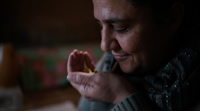 Mariana es una mujer adulta pero no mayor. Tiene los ojos cerrados, está concentrada sintiendo el aroma de algo que tiene en su mano ahuecada casi en su nariz. Esboza una sonrisa.